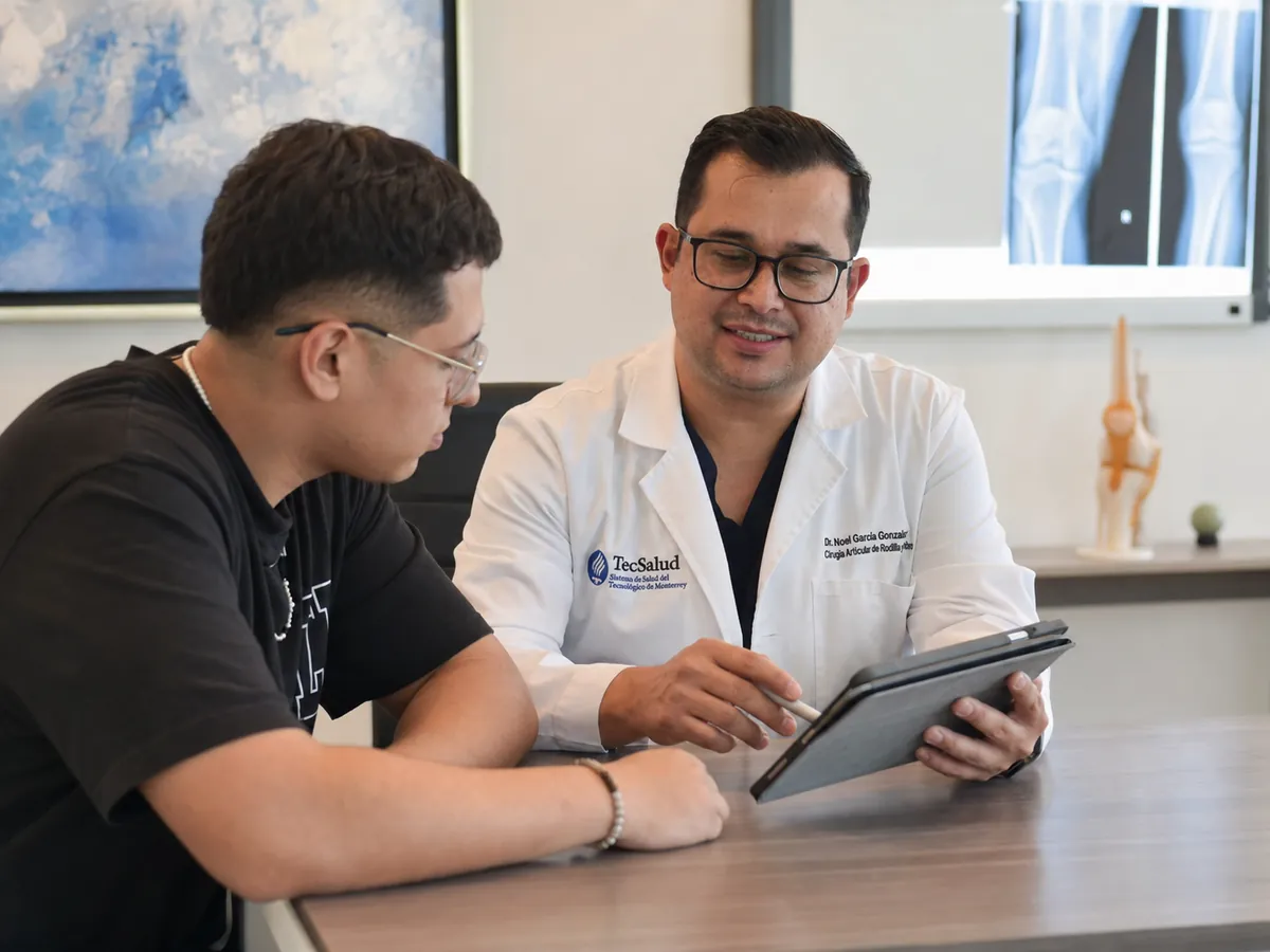 Dr. Noel García González revisando estudios de imagen con un paciente joven en su consultorio de Chihuahua